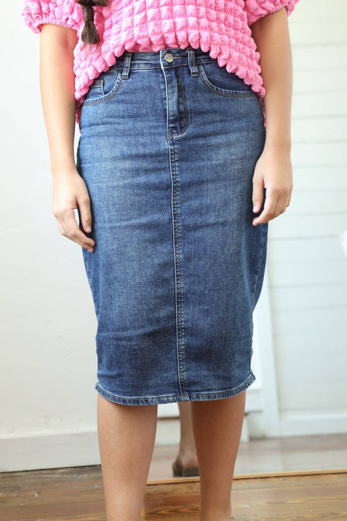 Knee-length medium blue denim skirt featuring a fitted silhouette, zipper and button closure, and front and back pockets.
