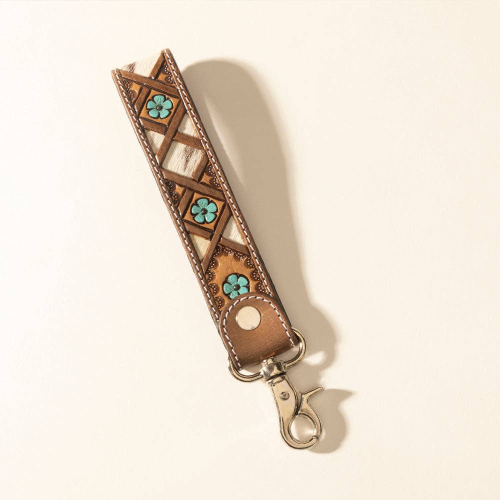 Handtooled leather keyfob featuring a mix of light and dark brown leather with turquoise flowers, compact design with metal clip.