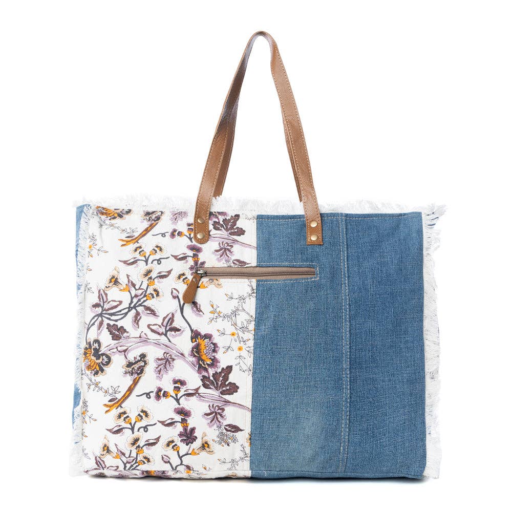 Floral cotton weekender bag featuring fringe detailing, a sturdy shoulder strap, and a side pocket for a water bottle.