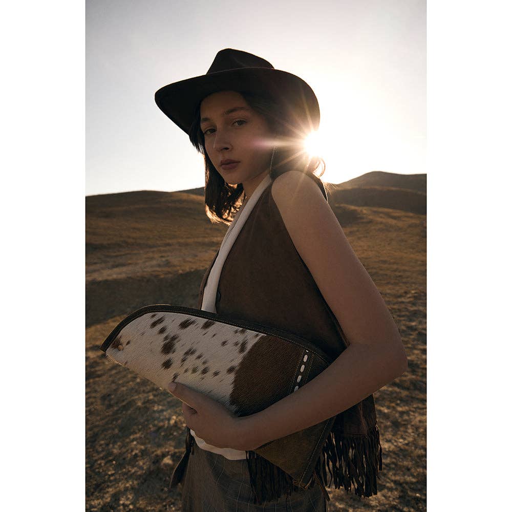 A person holding a Dusty Trail 15″ Gun Case featuring a unique hairon pattern and antiqued leather trim.