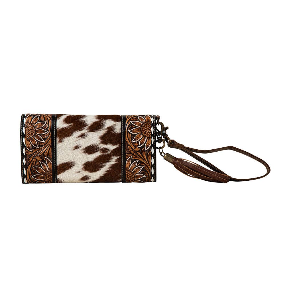 Hand-tooled floral wristlet wallet featuring a leather strap and snap-close flap, designed for stylish organization.