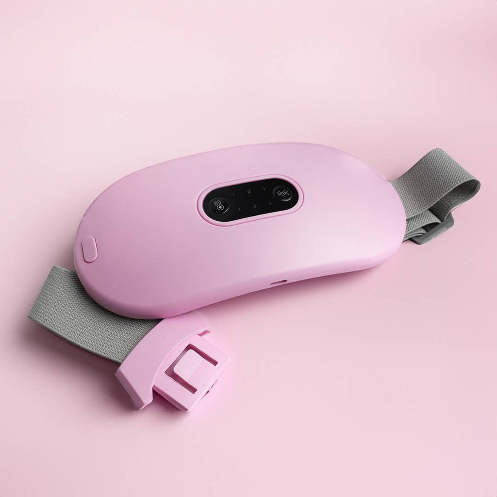 Pink heating device with buttons and adjustable gray strap, designed for targeted warmth and drug-free relief from cramps.