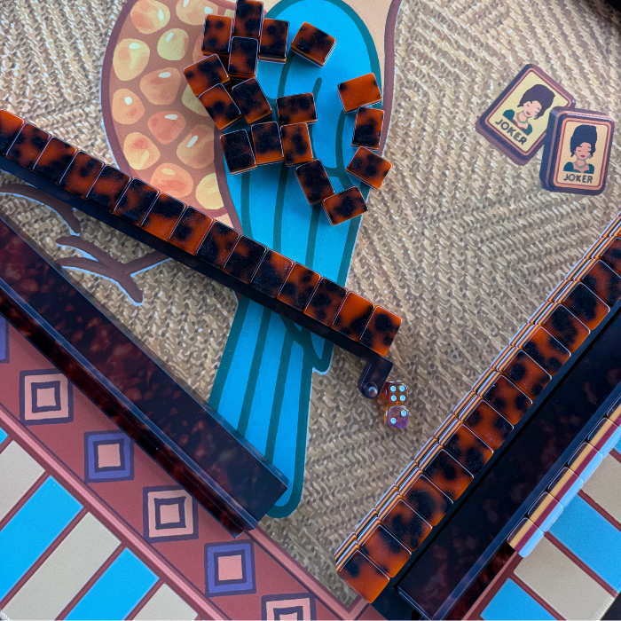 Mahjong set featuring tortoise shell pattern racks and pushers with arranged tiles, including marked 'JOKER' tiles.