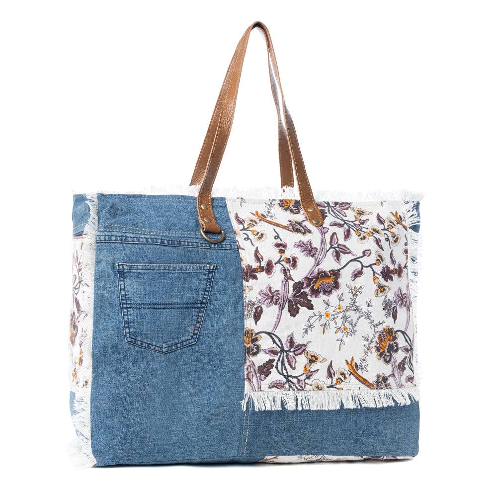 Floral cotton weekender bag featuring fringe detailing and a durable leather shoulder strap, perfect for your travels.