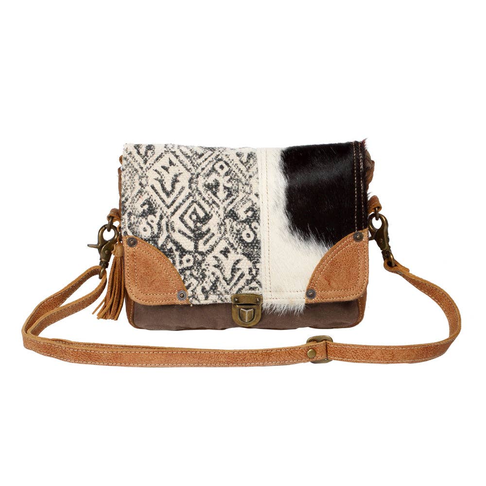 Geometric black-and-cream canvas messenger bag with hairon cowhide panel and tan leather accents.