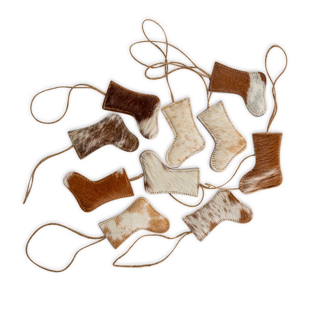 Ten unique brown hair-on hide stockings with stitched edges and jute hangers, displayed in a scattered layout.