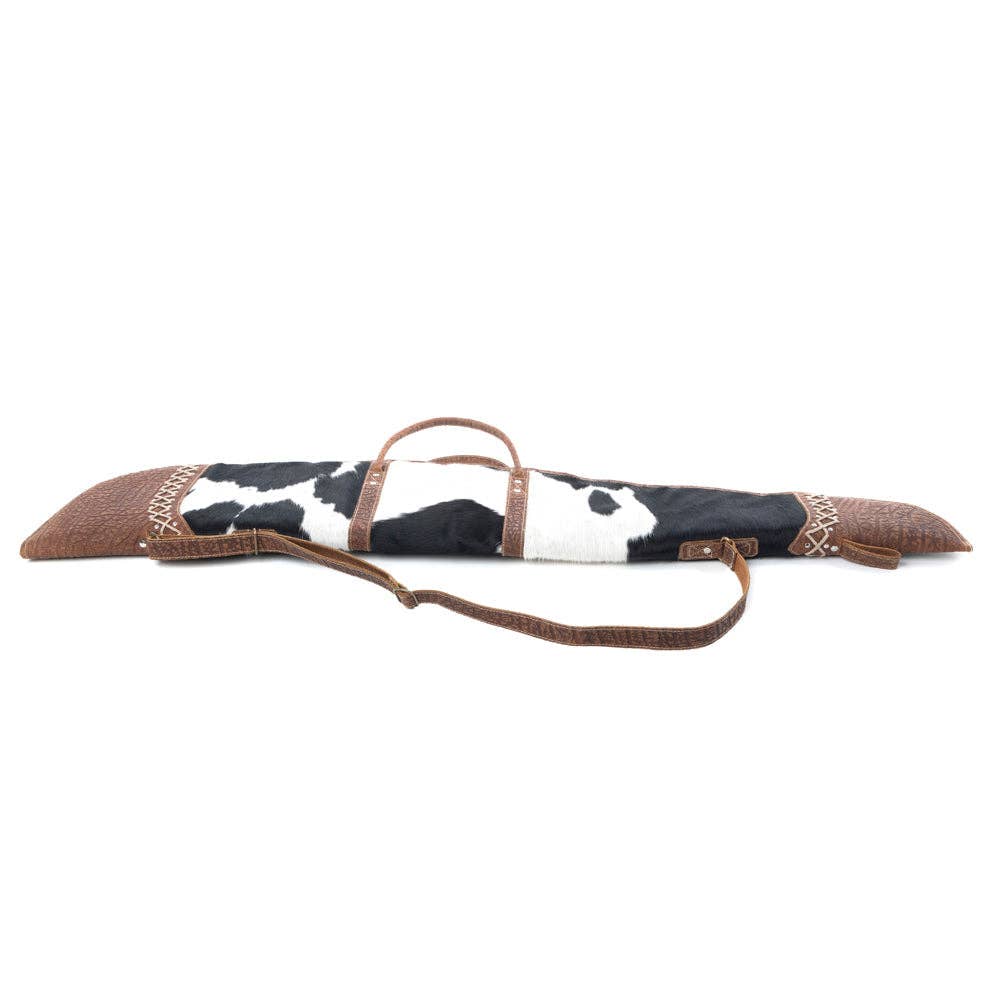 Black-and-white spotted hairon gun case with laced leather end caps, dual top handles, and an adjustable strap.
