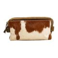 A rectangular pouch featuring a hair-on hide exterior with brown and white patterns, trimmed in leather with a zipper closure.