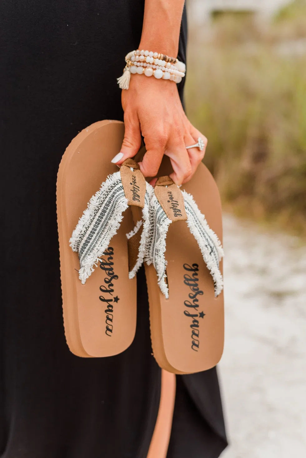 Frayed design flip flops with decorated straps and a tan sole, perfect for summer outings and vacations.