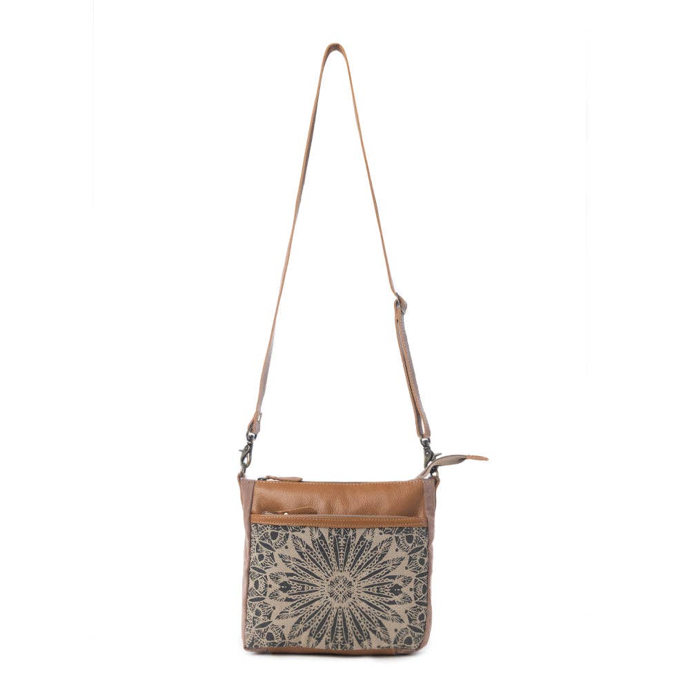Small crossbody bag featuring a canvas front with a decorative pattern and leather top, perfect for carrying essentials.
