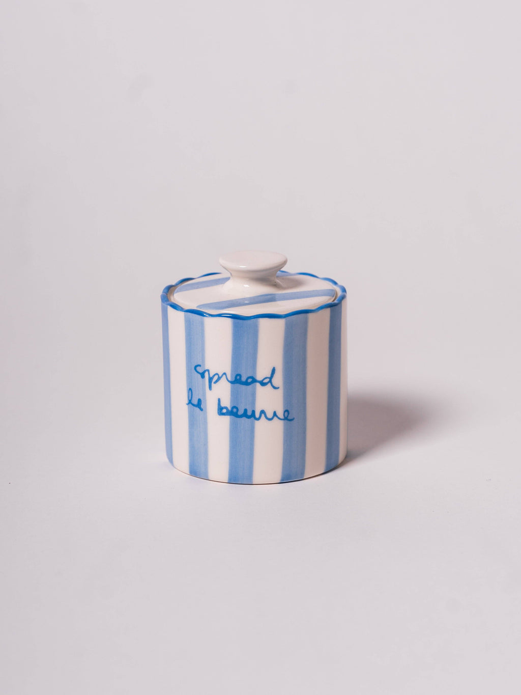Round butter keeper with scallop edge, featuring blue and white stripes and the text 'spread le beurre.'