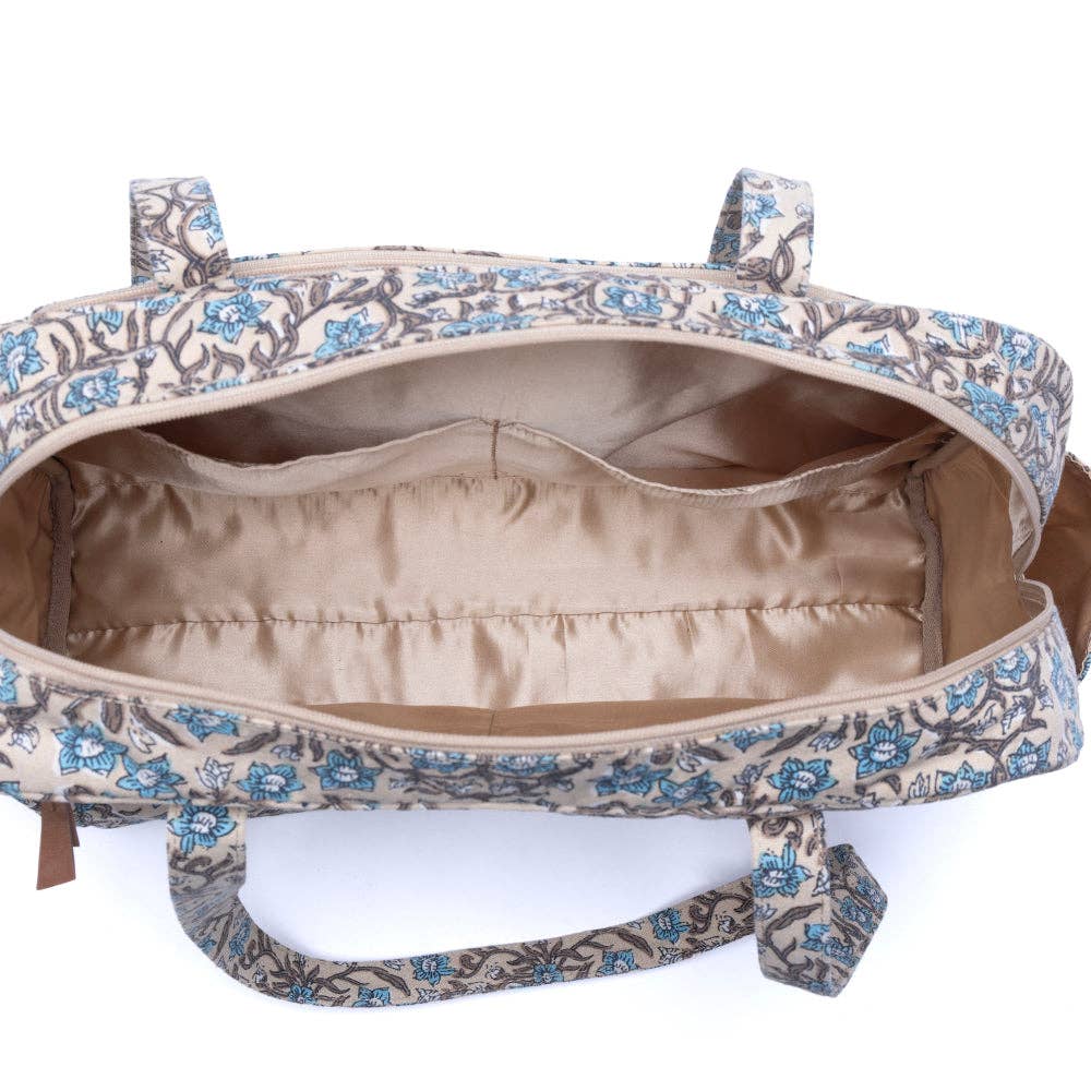 Spacious dusty teal diaper bag with floral pattern, featuring organized interior pockets and two sturdy handles.