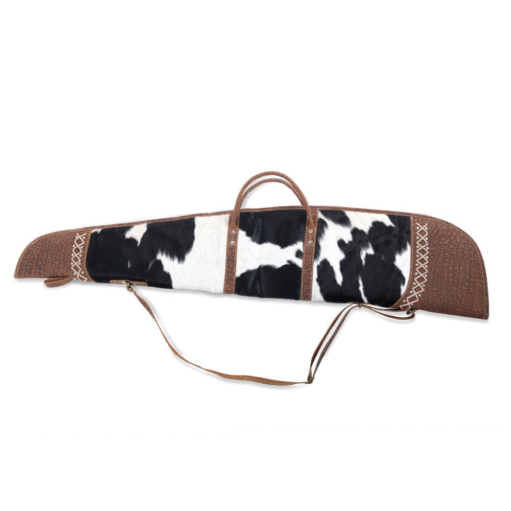 Black-and-white spotted cowhide gun case with laced leather end caps, dual top handles, and an adjustable strap.