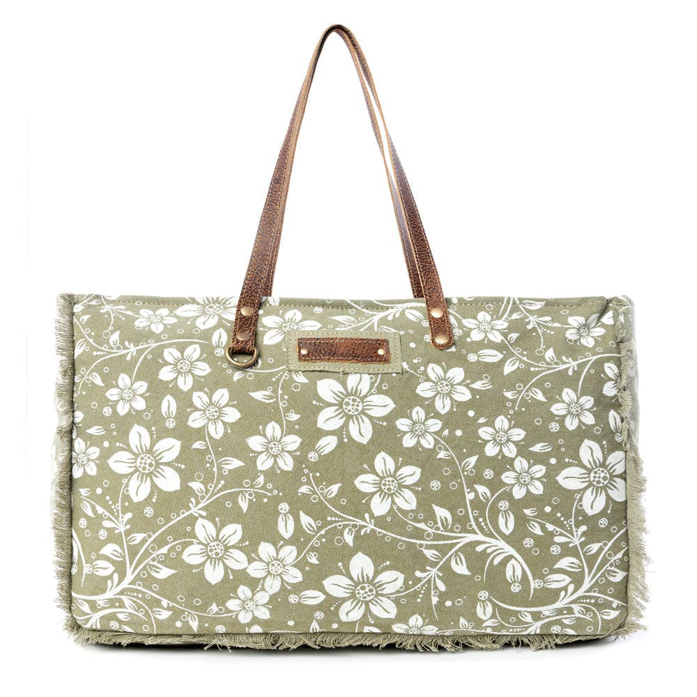 Floral weekender bag with a light green background, leather top handles, and zipper closure featuring a frayed edge design.