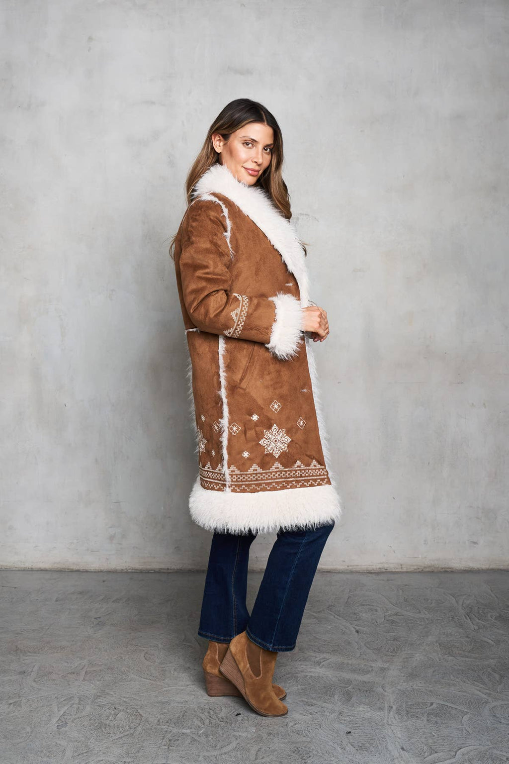 Rich camel faux suede coat with shearling trim, featuring delicate embroidery on the front and sleeves. Mid-length with inseam pockets.