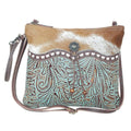 Turquoise embossed leather crossbody bag with brown-and-white cowhide back and decorative beads on the closure.