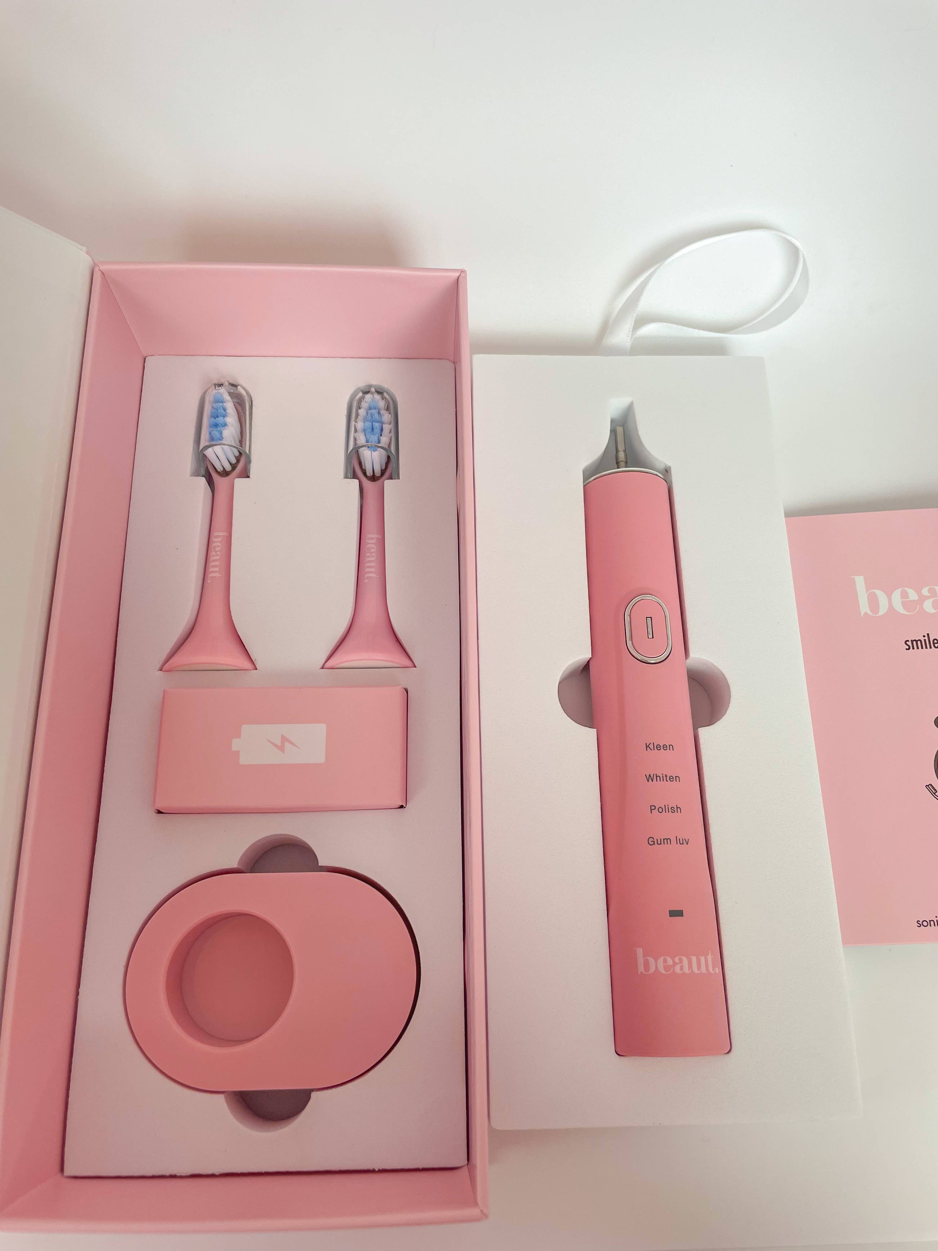 Pink Smile Kleen Sonic Vibration Toothbrush with two replacement brush heads and a charging base, featuring three settings.