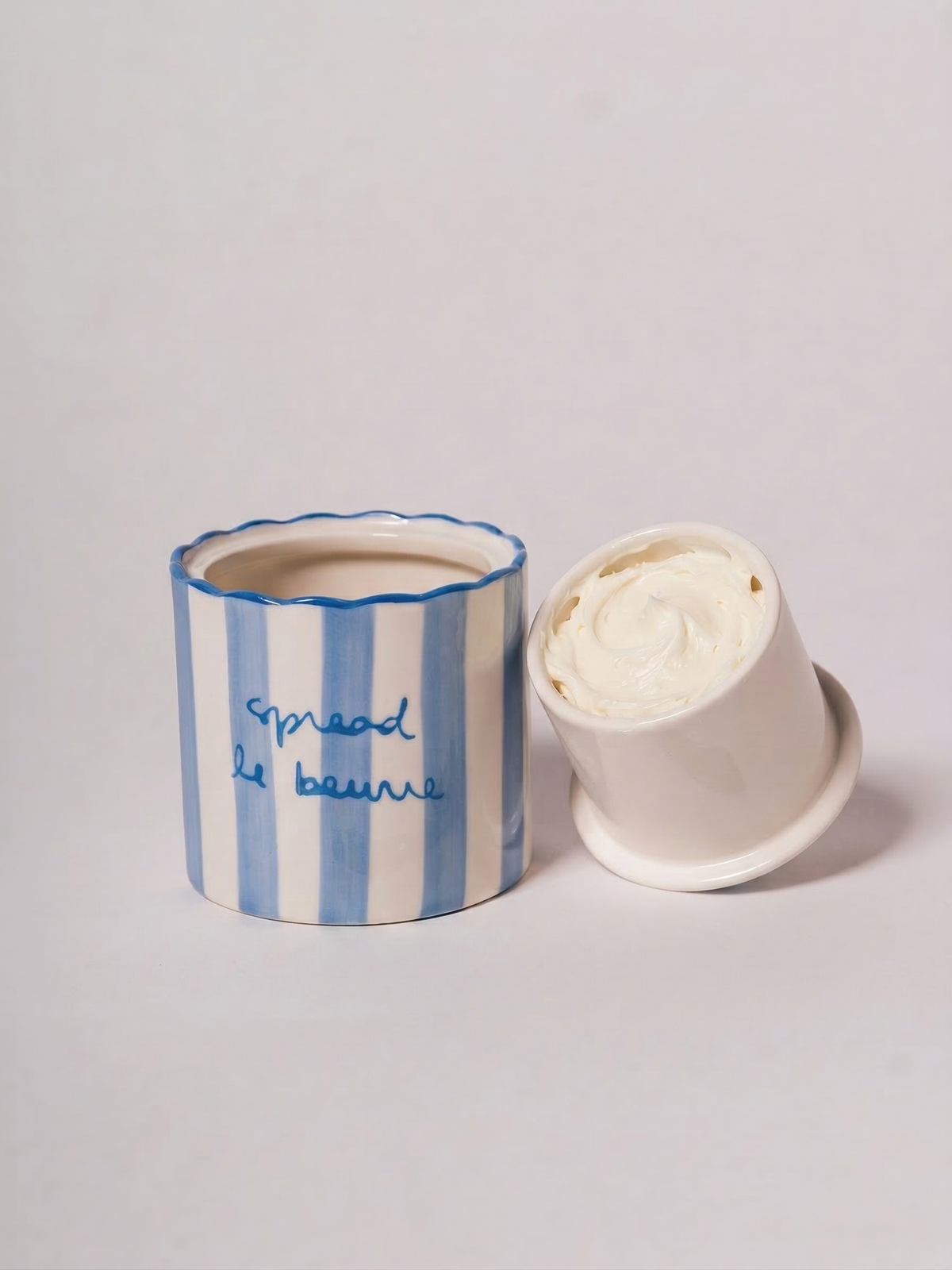 Scalloped butter keeper with blue stripes and text that reads 'spread le beurre,' perfect for adding charm to your kitchen.