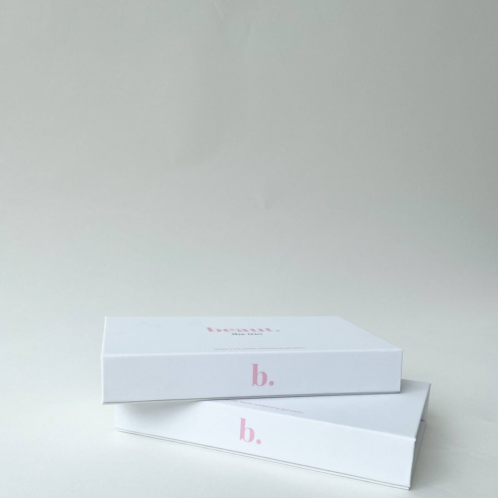 Two stacked white boxes featuring a pink letter 'b.' containing the 3 Smile Pens Pack: The Trio - Teeth Whitener.