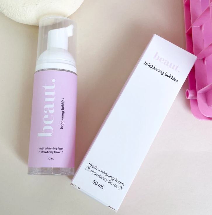 Pump bottle of Brightening Bubbles with a pink label, featuring teeth whitening foam in strawberry flavor.