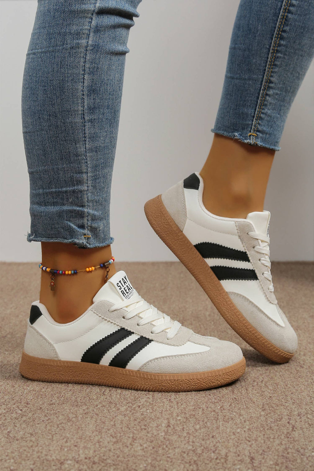 Color block patchwork sneakers in white with black stripes and a light-colored sole, perfect for casual wear.