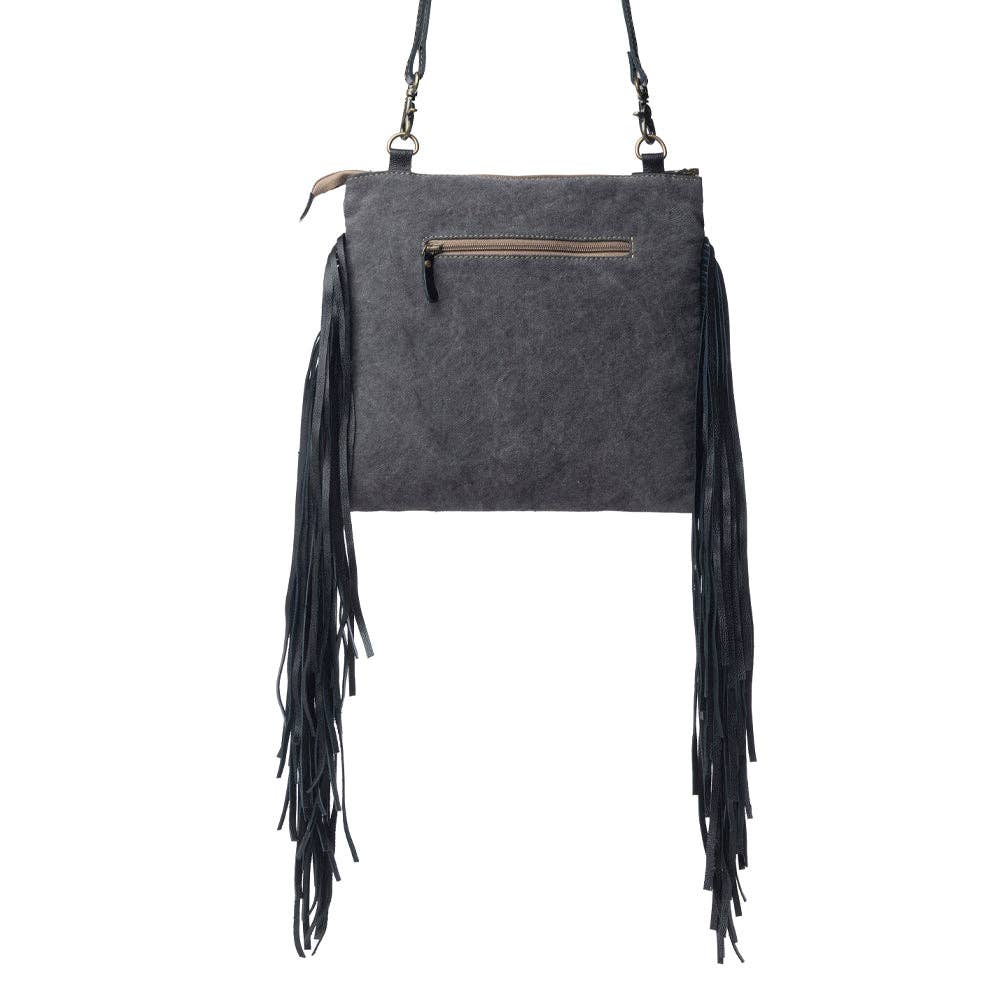 Fringed hand-tooled bag featuring a zippered top, detachable shoulder strap, and black leather side fringes.