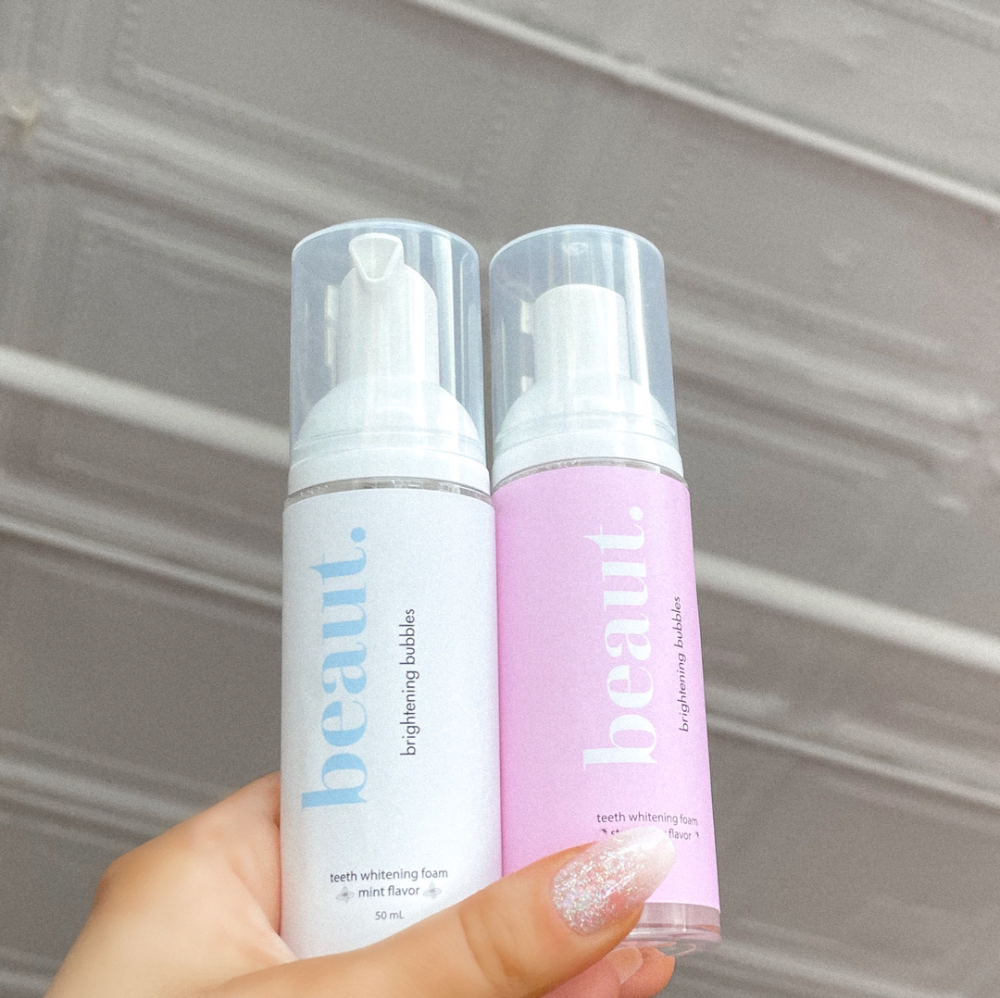 Two bottles of Brightening Bubbles in blue and pink packaging with pump dispensers, labeled teeth whitening foam.