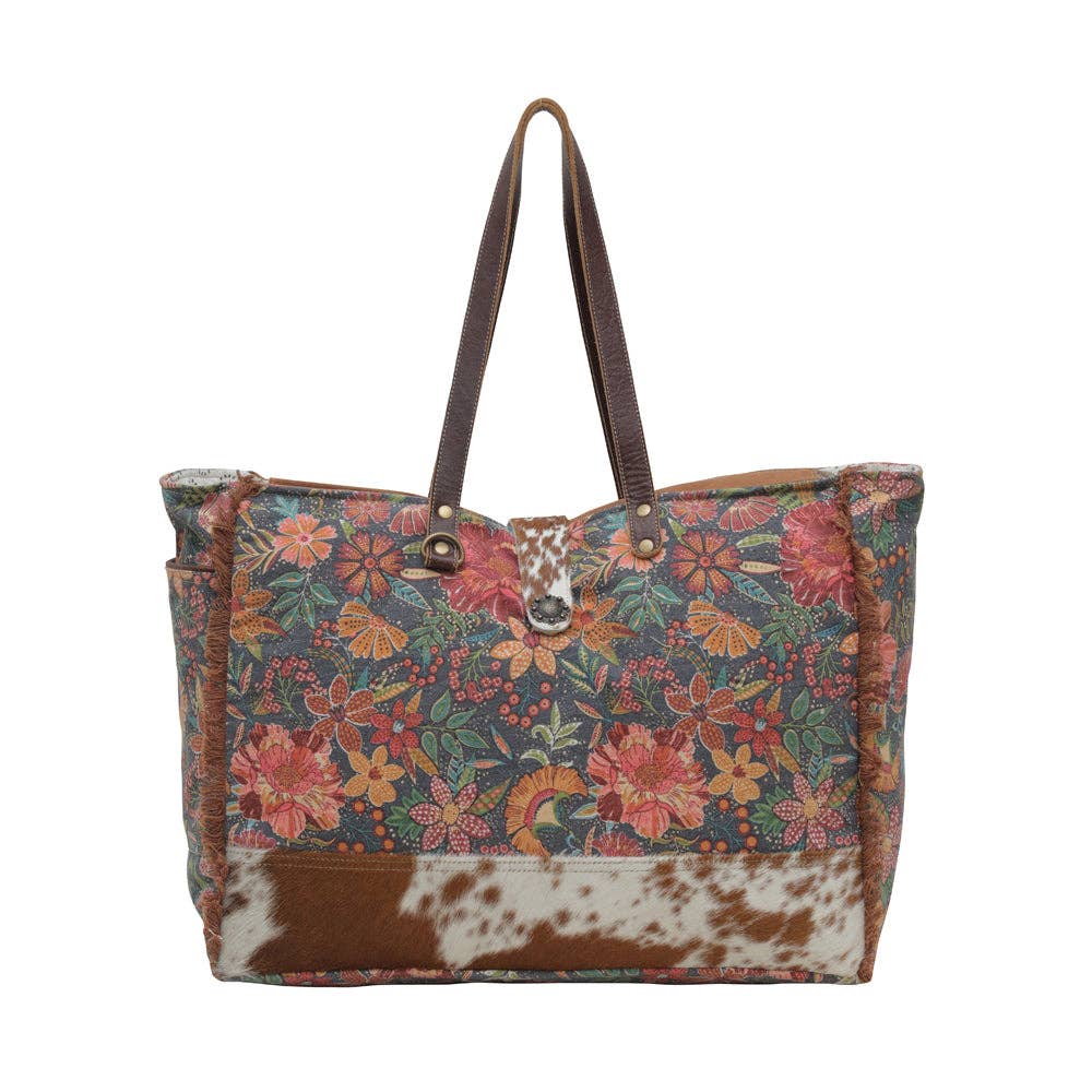 Floral weekender bag with hairon material at the bottom and sturdy handles, perfect for weekend adventures.