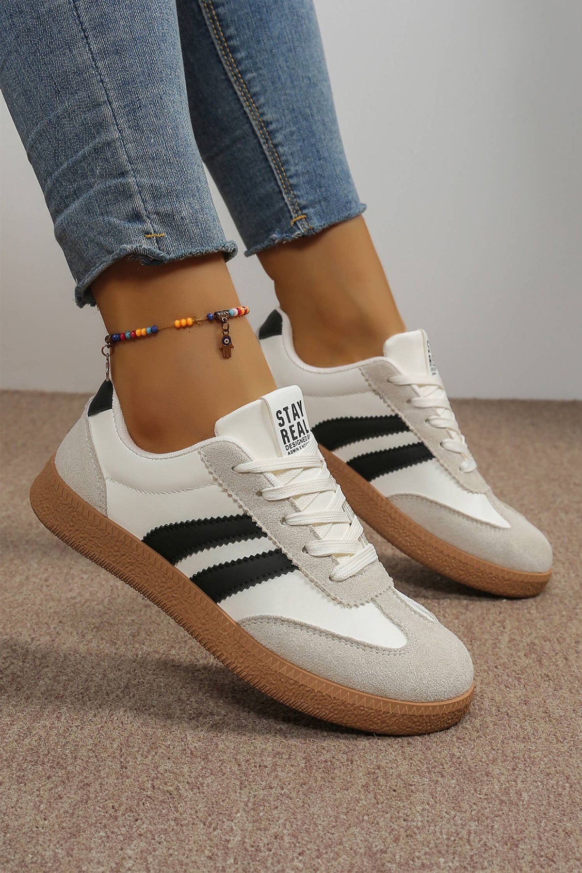 Color block patchwork sneakers in white, black, and gray with a lace-up closure and textured sole for a sporty look.