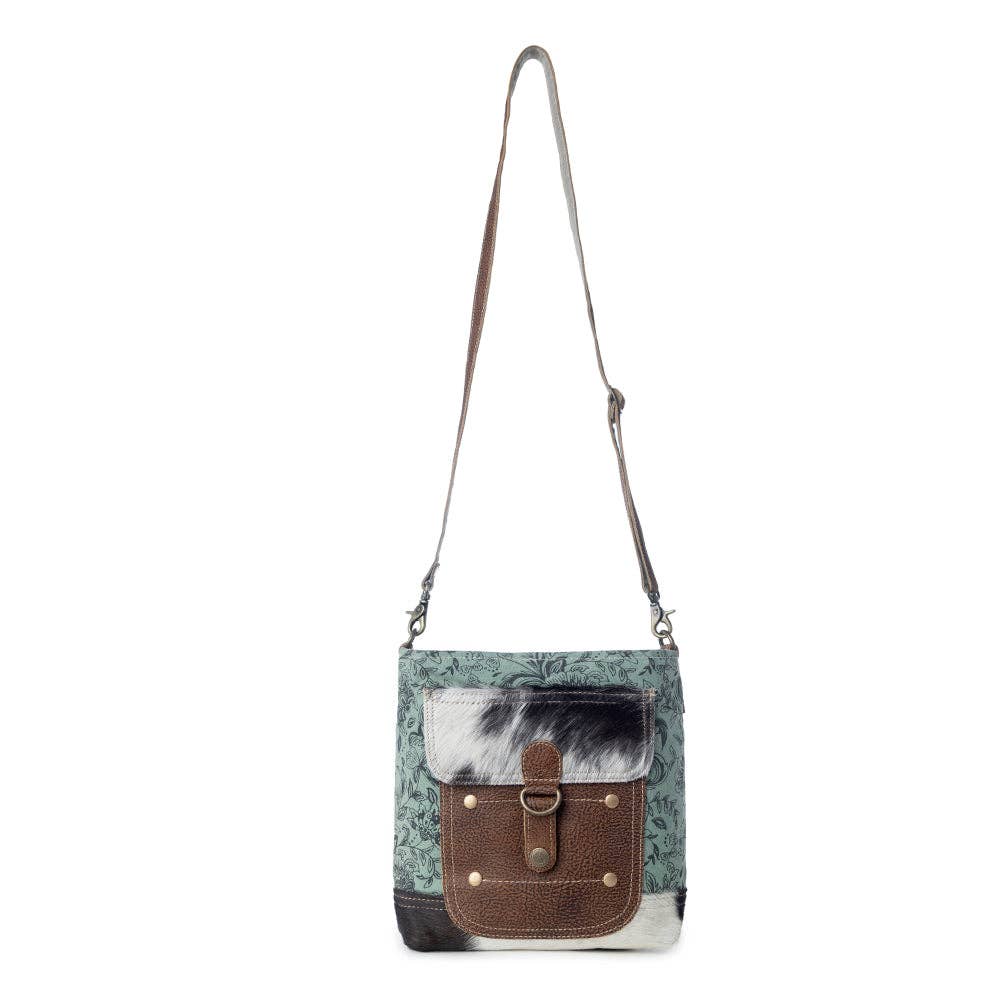 Shoulder bag featuring a patterned front, solid strap, and flap closure with button, perfect for everyday use.