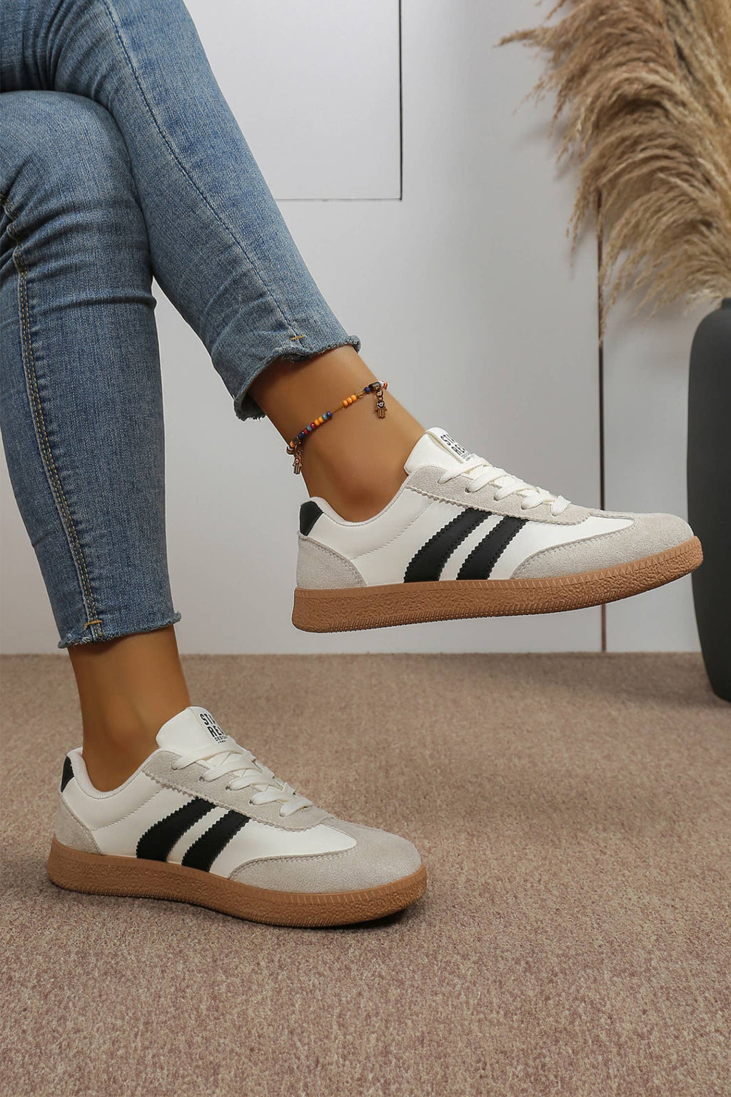 Color block patchwork sneakers featuring a white upper, black stripes, and light gray toe cap for a sporty varsity look.