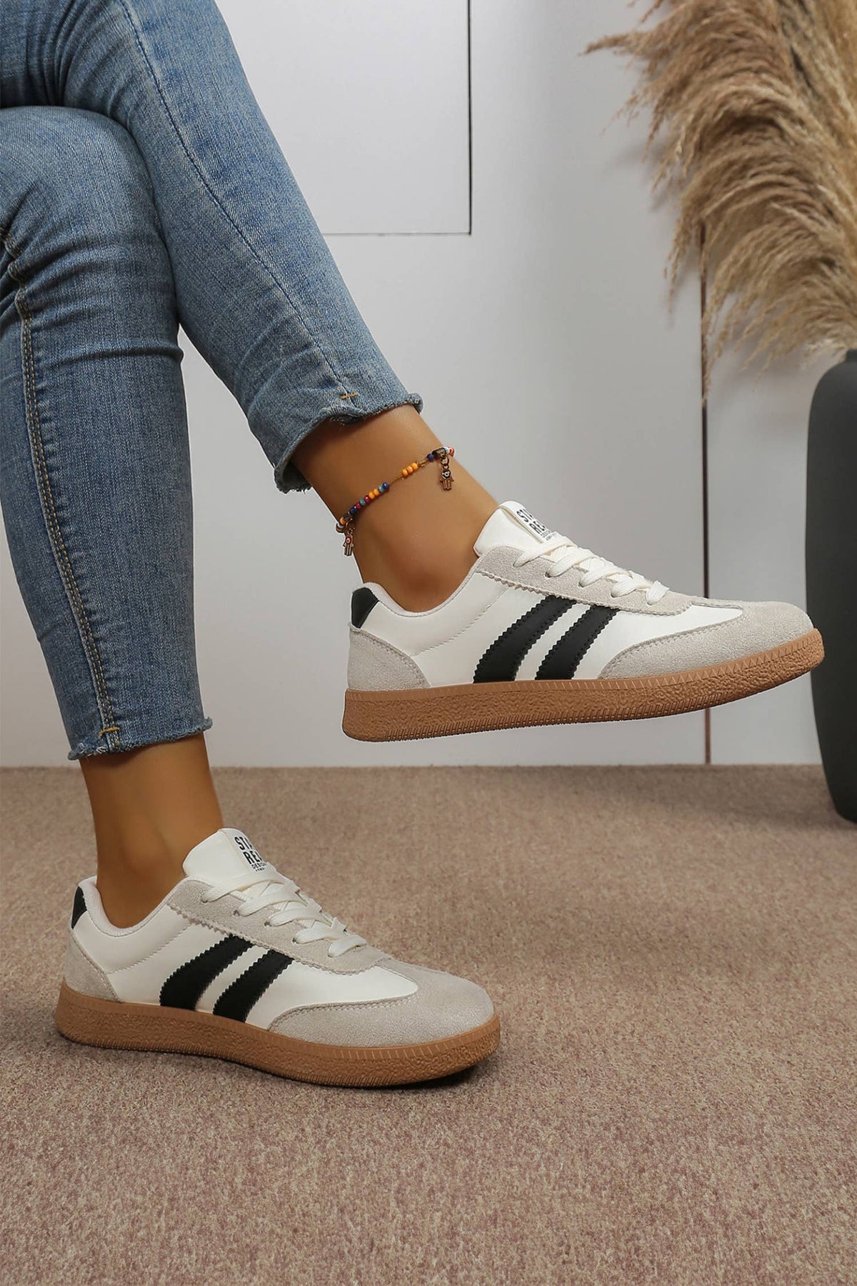 Color block patchwork sneakers featuring a white upper, black stripes, and light gray toe cap for a sporty varsity look.