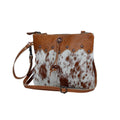 Brown leather and hairon handbag with decorative elements, strong back zipper, and adjustable leather straps.