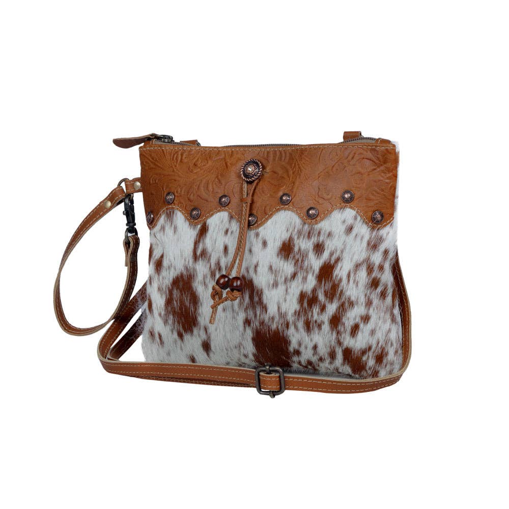 Brown leather and hairon handbag with decorative elements, strong back zipper, and adjustable leather straps.