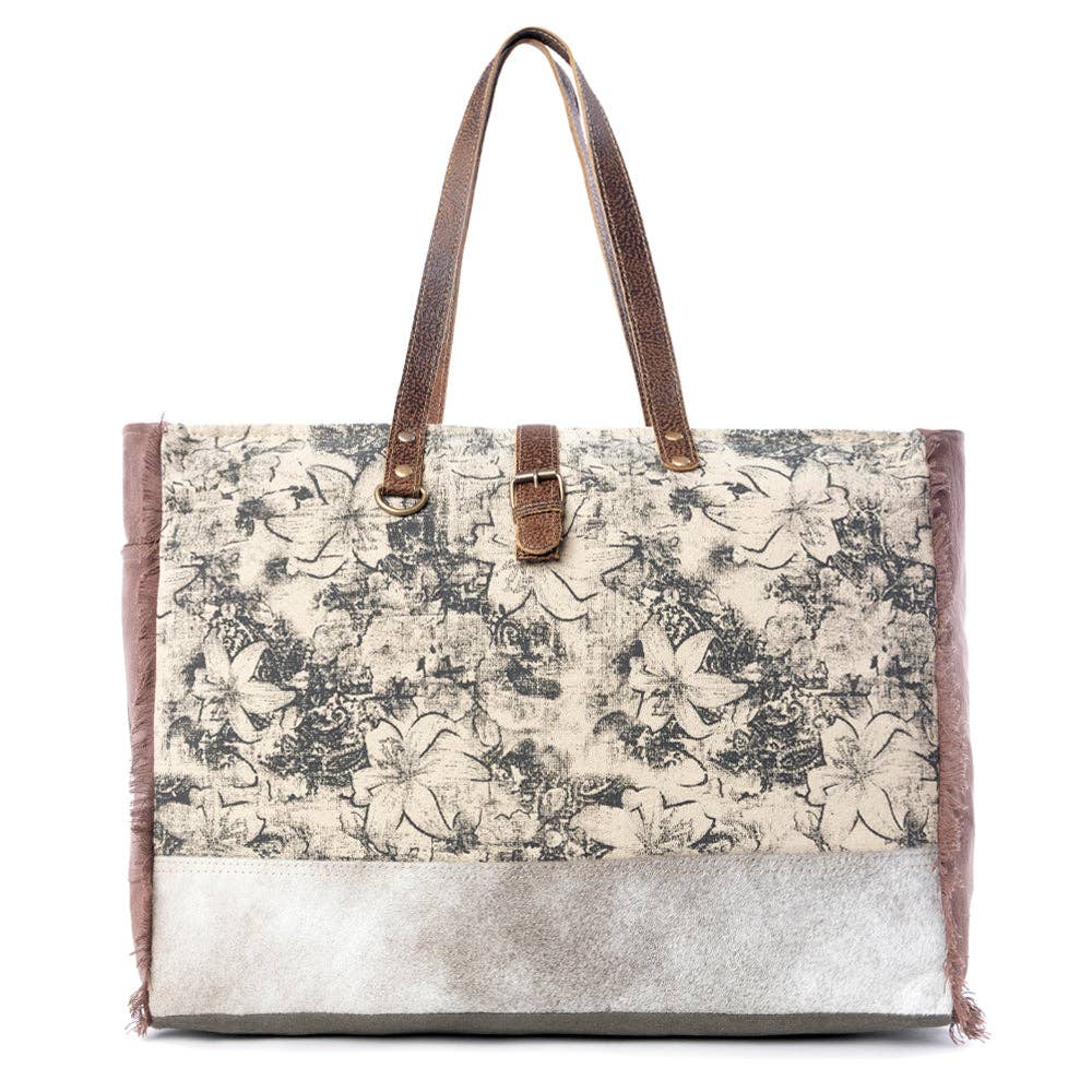 Floral canvas weekender bag with leather accents and top handles, featuring a spacious main compartment for weekend getaways.