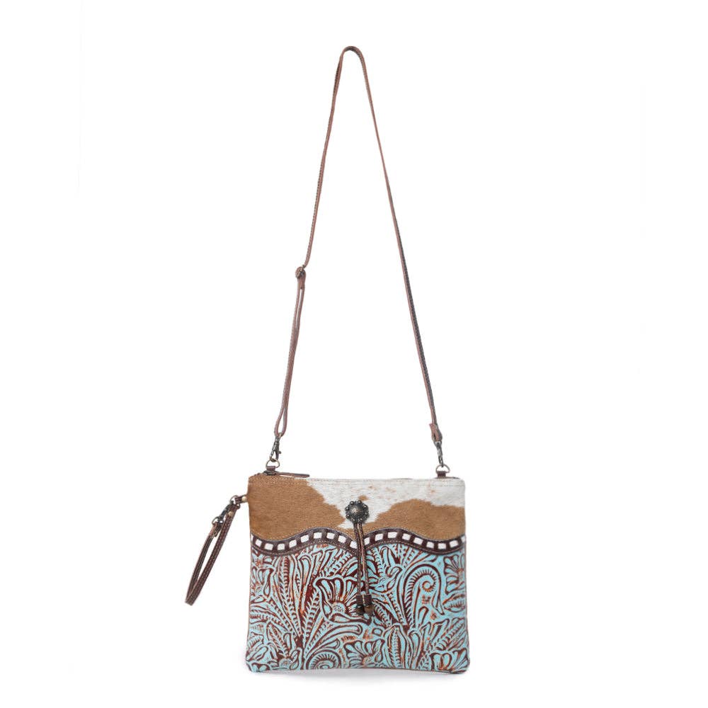 Turquoise embossed leather crossbody bag featuring a stylish brown-and-white cowhide accent. Perfect for everyday use.
