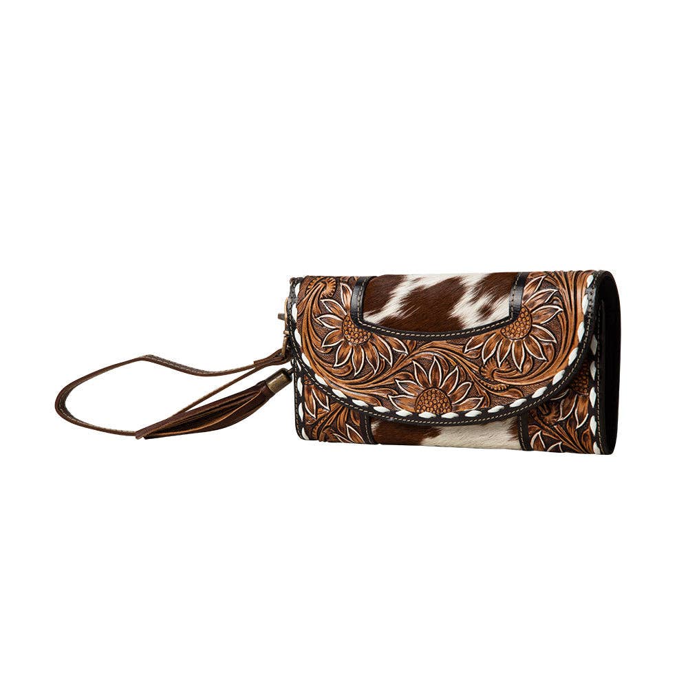 Hand-tooled floral wristlet wallet featuring a zippered pocket and snap-close front flap.