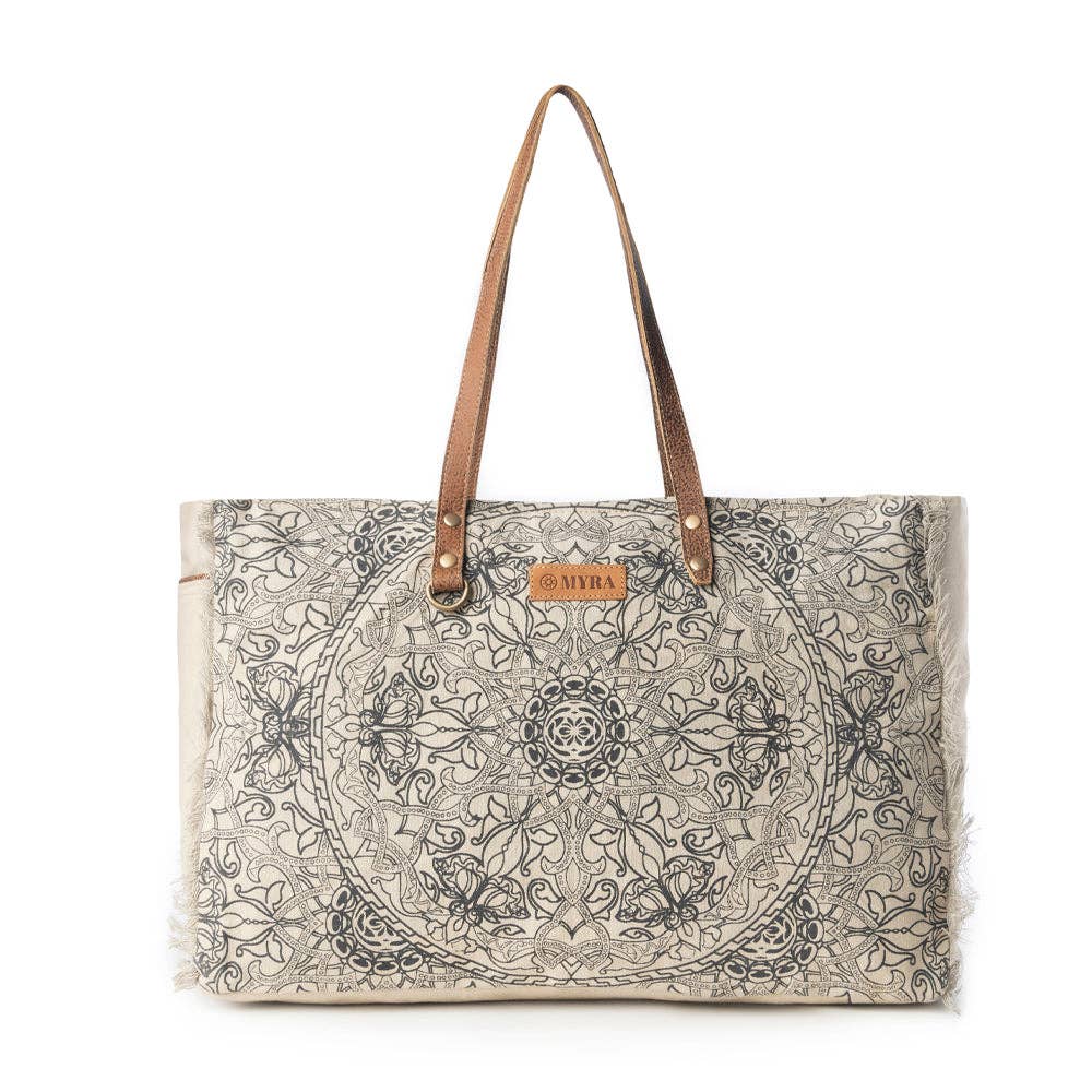 Ivory weekender bag featuring a vintage mandala print, leather handle accents, and fringe edges, perfect for travel.