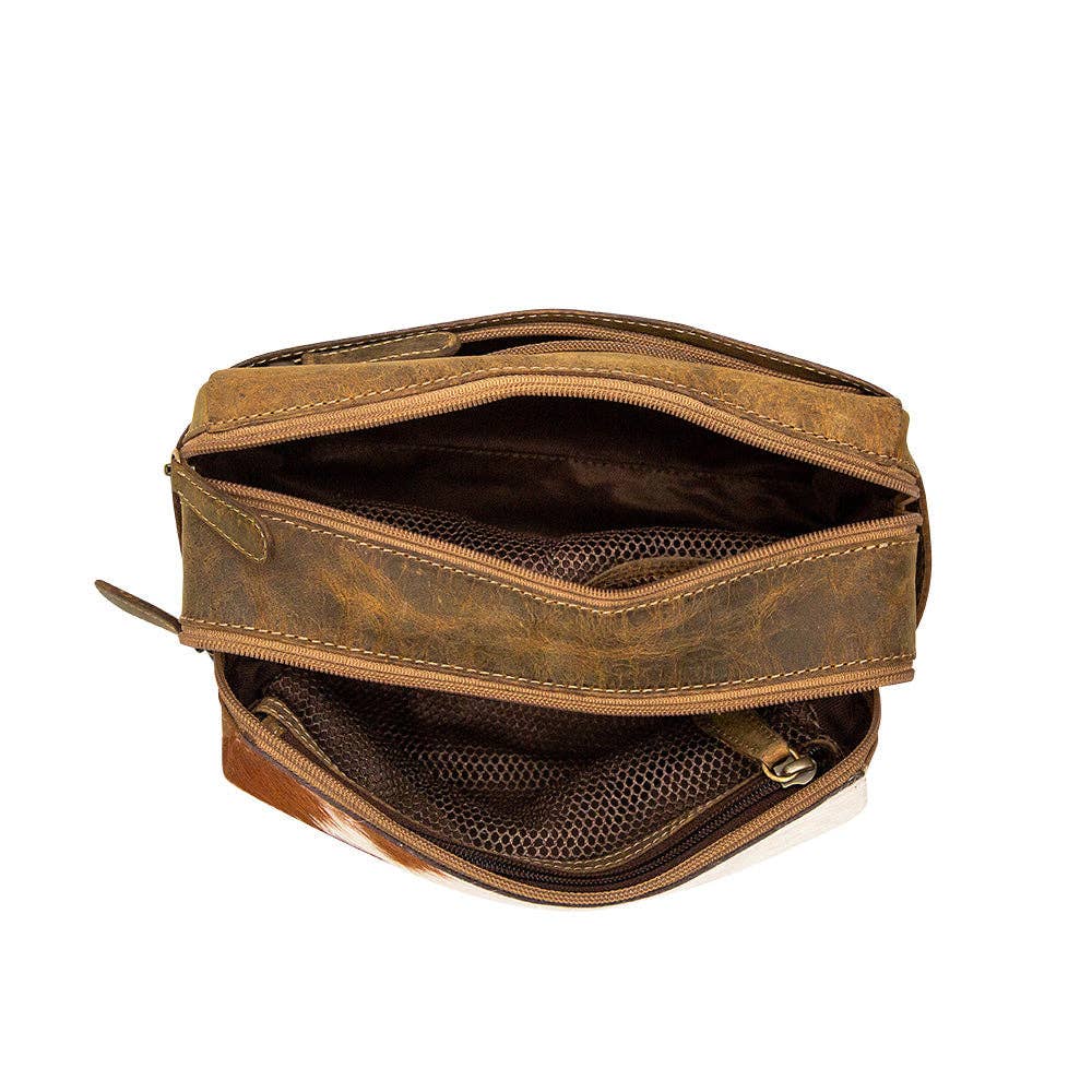 A structured brown bag with a zippered opening and mesh compartment, showcasing the Ferald Shaving Kit in hair-on hide and leather.