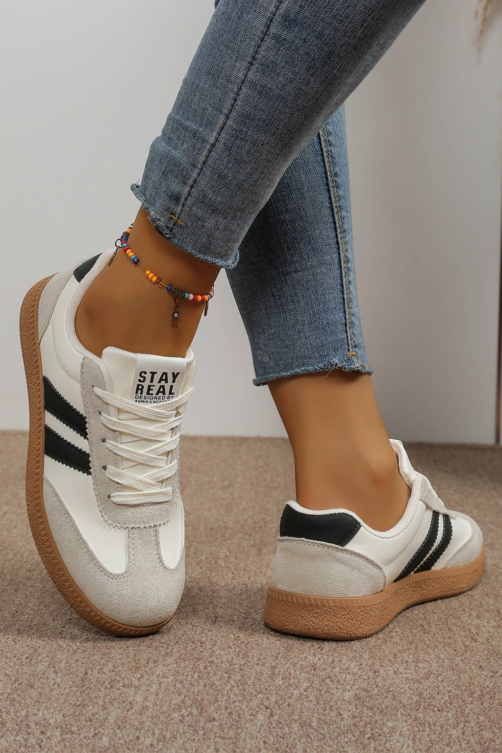 Color block patchwork sneakers in white, black, and gray with sporty stripes and a textured sole for casual style.