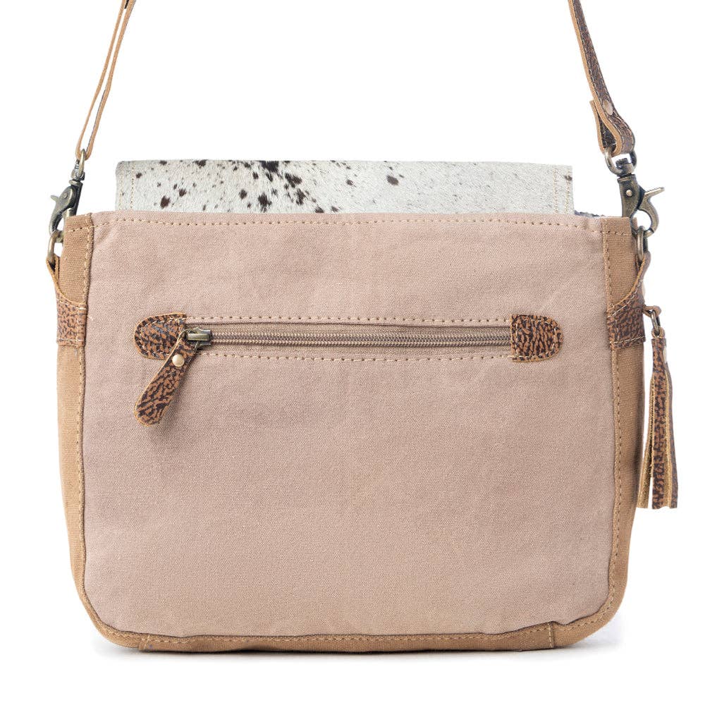 Rugged messenger bag featuring a unique hairon flap, zippered back pocket, and a stylish shoulder strap.