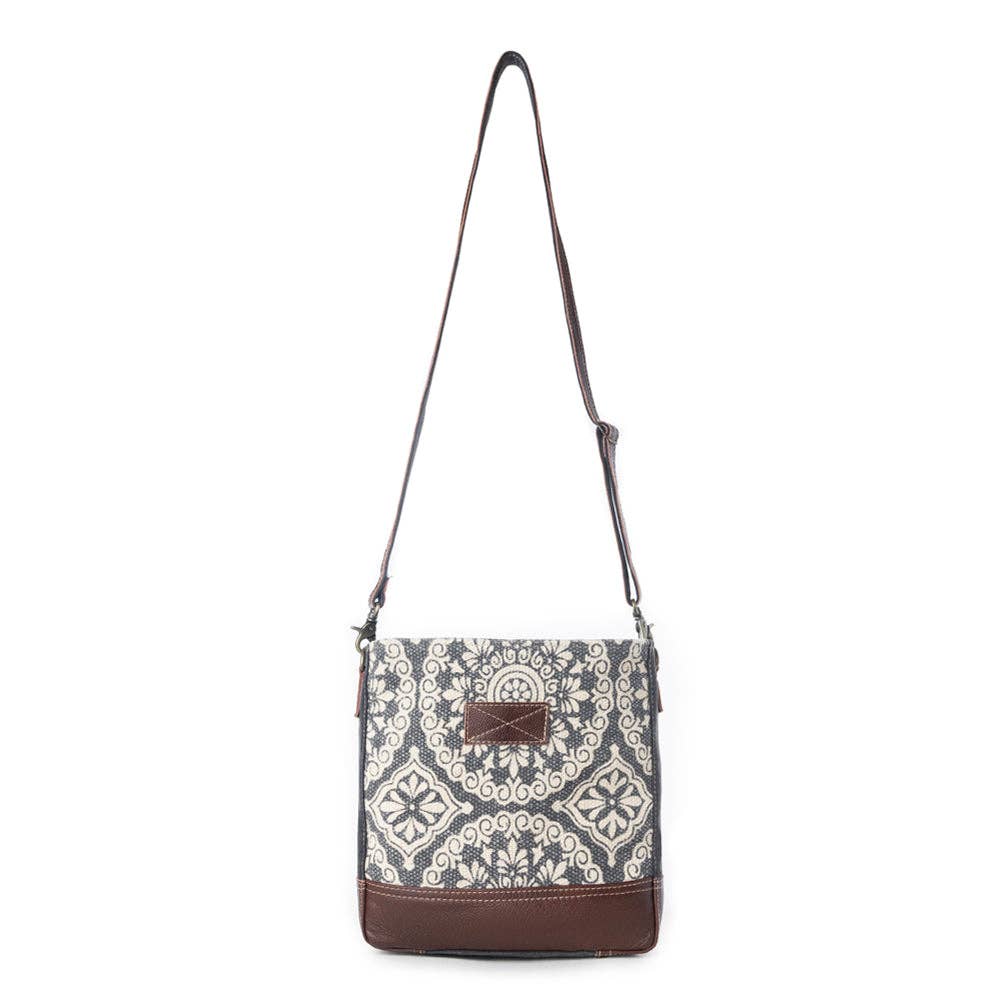 A stylish shoulder bag featuring a patterned design with light and dark colors, a long strap, and a flap closure.