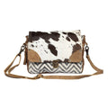 Rugged messenger bag featuring a hairon flap with a spotted pattern, chevron design, and leather accents in browns and creams.