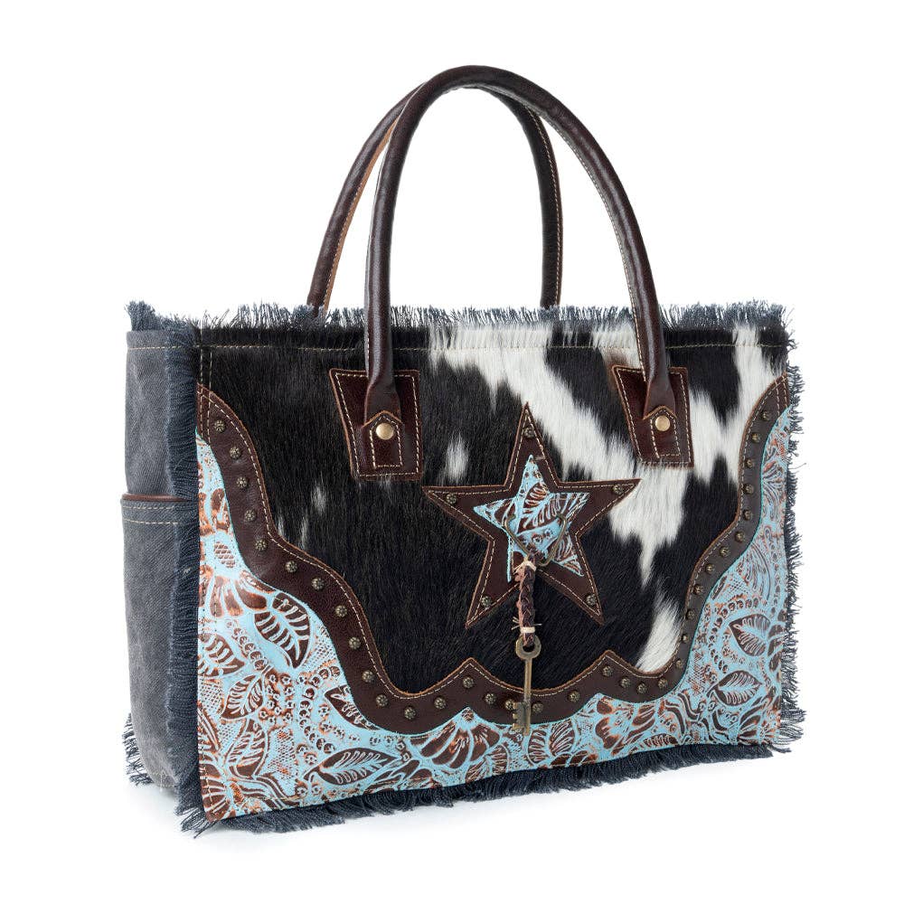 A stylish Articulate Canvas & Hairon Bag featuring a star motif, frayed edges, and decorative studs for a bold western look.