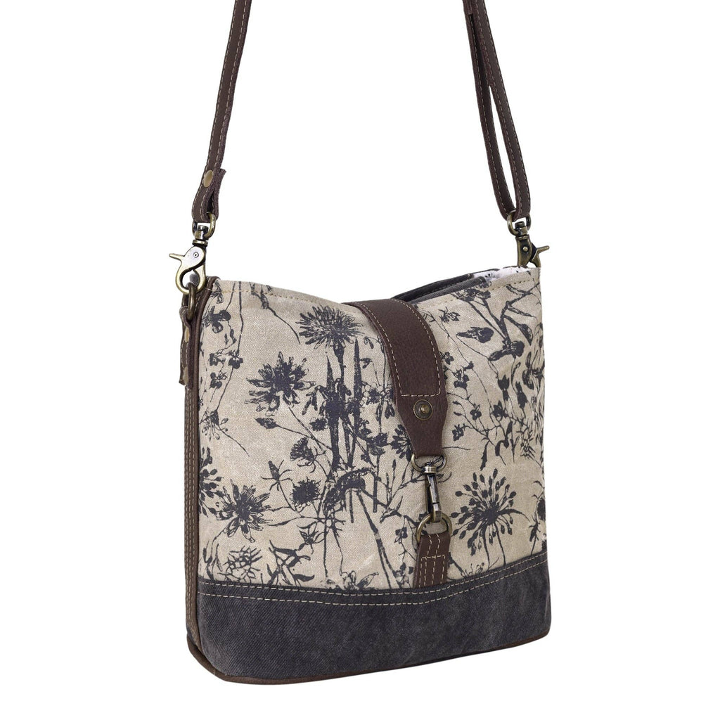 Floral canvas shoulder bag featuring a front lock closure and adjustable leather straps in a stylish two-tone design.