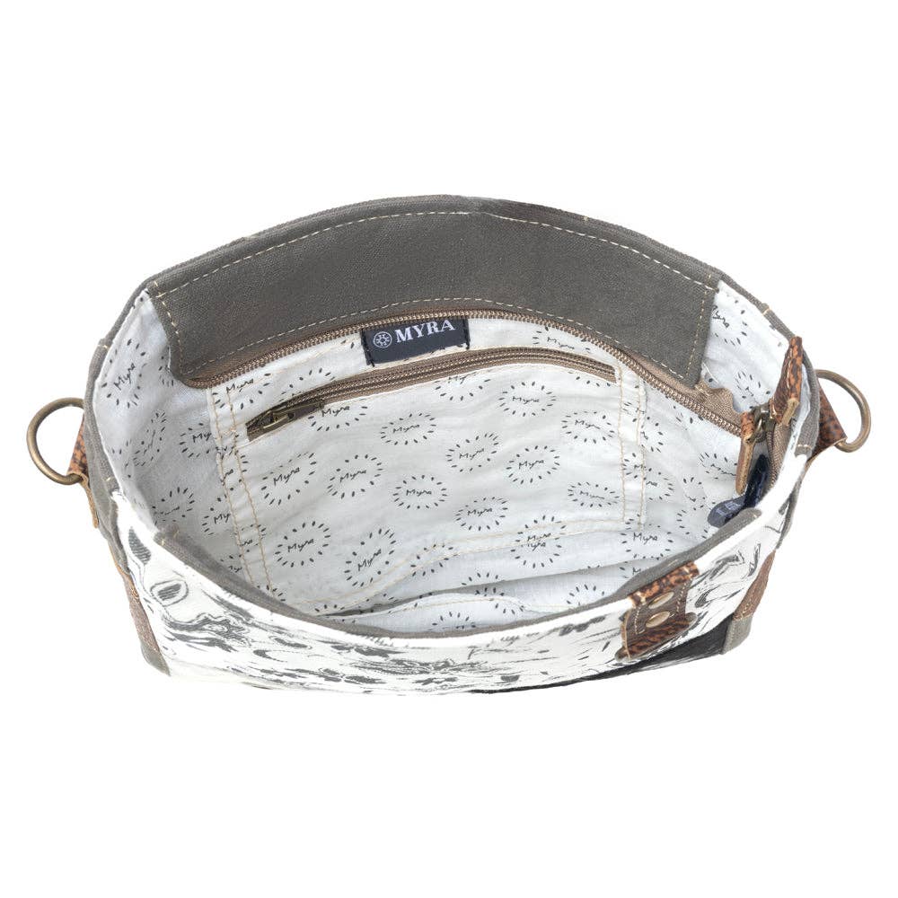 Floral canvas shoulder bag featuring a hairon front panel and a zippered top closure, perfect for everyday use.