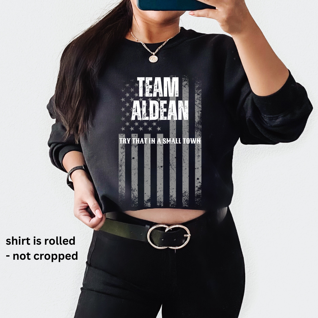 Graphic sweatshirt featuring 'TEAM ALDEAN' and 'TRY THAT IN A SMALL TOWN' with a flag motif and rolled sleeves.