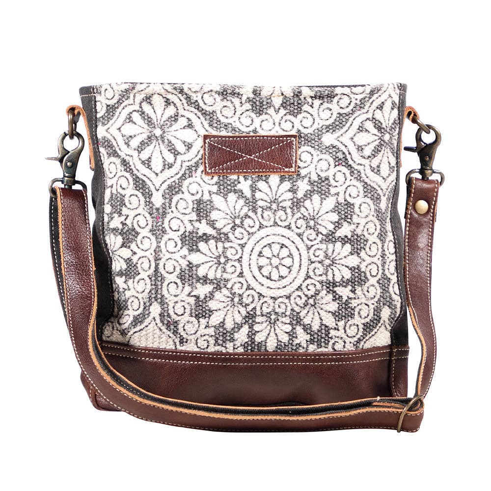 A stylish shoulder bag featuring a mix of light and dark patterned fabric with leather accents, perfect for everyday use.