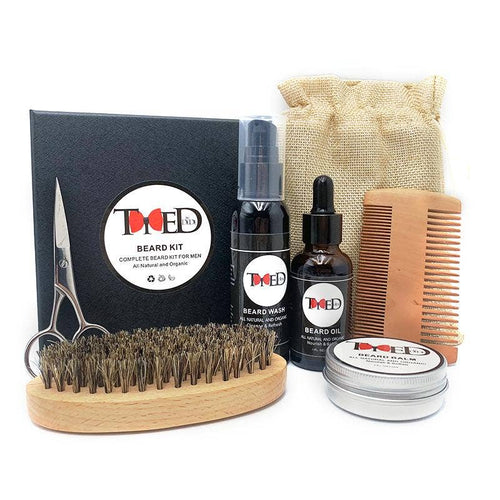 Beard grooming care kit featuring a beard brush, comb, scissors, oil, wash, and balm in an organized black box with burlap.