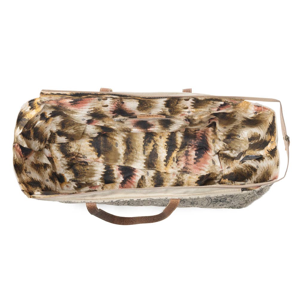 Ivory weekender bag featuring a vintage mandala print, soft fringe edges, leather handle accents, and practical pockets.